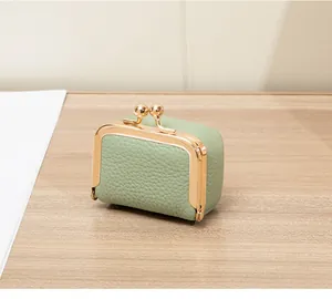 Détail du mini sac vert pois en cuir grainé avec fermoir clic-clac doré sur bois