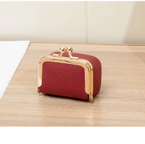 Gros plan sur le cuir grainé et le fermoir en métal doré de cette mini pochette bijou