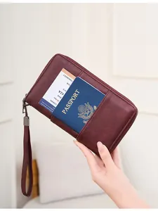 Detail of wine red RFID passport wallet holding tickets and boarding passes in hand
