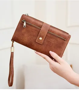 Dettaglio del portafoglio vintage marrone con protezione RFID, zip e cinturino da polso