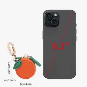 Mini orange leather coin purse keychain showing size comparison with 6.1 inch phone