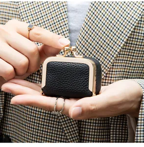 Mini porte-monnaie en cuir noir avec fermoir doré vintage tenu en main
