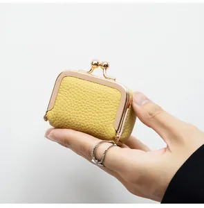 Détail du mini porte-monnaie en cuir jaune avec motif litchi et fermoir en métal