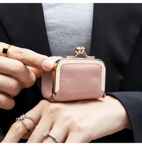 Mini porte-monnaie en cuir rose avec grain litchi et fermoir doré tenu par un modèle