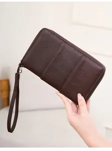 Deep brown RFID passport wallet in lychee grain leather with wristlet held by hand