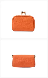 Gros plan sur la texture cuir orange et le fermoir kiss-lock doré d'une mini pochette à monnaie