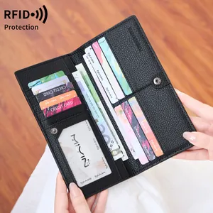 Minimalist long black RFID blocking wallet in lychee leather held by hand outdoors