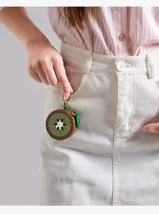 Vue détaillée d'un mini porte-monnaie kiwi en cuir PU accroché sur une jupe blanche