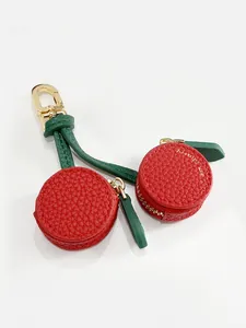 Detail of red cherry coin purse pendant with textured leather and gold carabiner