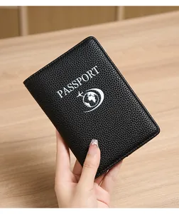 Close-up of black litchi pattern leather passport holder with RFID blocking and white graphics