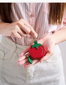 Détail du porte-monnaie tomate montrant la texture litchi rouge et le zip feuille verte