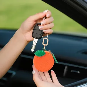 Porte-monnaie mignon en forme d'orange en cuir avec porte-clés doré sur fond d'intérieur auto