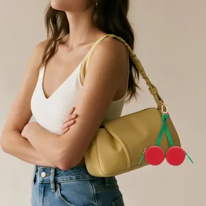 Mini monedero con forma de cereza en cuero rojo colgado de un bolso amarillo