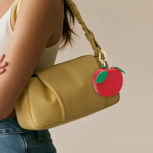 Mini red apple leather coin purse keychain hanging on a stylish handbag strap