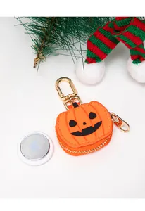 Detalle del soporte de cuero para AirTag con diseño de calabaza naranja y clip de metal dorado