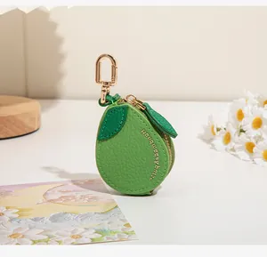 Détail d'une mini pochette en cuir en forme de fruit vert avec zip doré et crochet