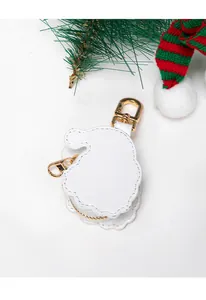 Detail of white leather Santa Claus coin purse keychain with gold hardware and pine accents