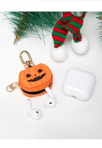 Detalle del colgante de calabaza naranja con herrajes dorados y auriculares blancos dentro