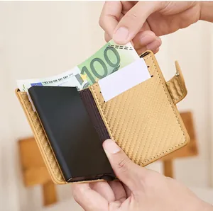 Détail du portefeuille en fibre de carbone doré avec un billet de 100 euros à l'intérieur