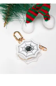 Detalle de mini estuche de telaraña con araña de purpurina y mosquetón dorado
