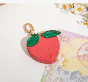 Détail du porte-monnaie en cuir rose en forme de pêche avec feuilles et crochet doré