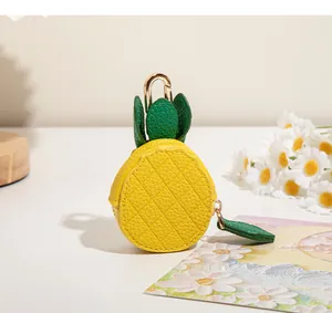 Détail du mini porte-monnaie ananas en cuir avec feuilles vertes et mousqueton doré