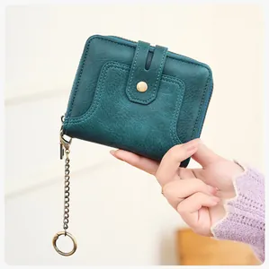Detail of teal leather RFID wallet with vintage chain and button closure held by hand