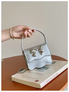 Macro detail of silver PU handbag featuring a metallic bow and wavy edge design