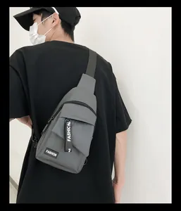 Detail of dark grey nylon chest bag featuring fashion logo and decorative strap handle