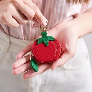 Petit porte monnaie en cuir forme tomate avec fermeture éclair dorée tenu par un modèle