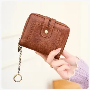 Detail view of brown RFID wallet with pebbled texture, zipper closure and metal keychain