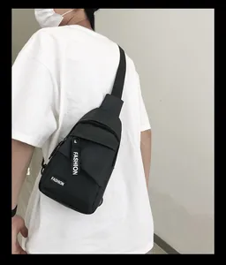 Detail view of the durable black nylon chest bag with white FASHION lettering and zippers