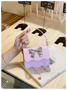 Detail of pink PU mini bag featuring a wavy flap and silver metallic bow decoration