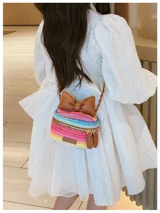 Detail of colorful rainbow woven crossbody bag featuring a large brown leather bow accent