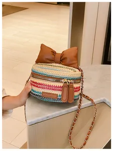 Detail of multi-color woven straw bag with leather bow and metal chain strap