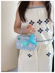 Dettaglio di coda di sirena con paillettes, conchiglia e stella su borsa blu