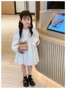 Detail of child wearing a gradient woven cylinder crossbody bag with a brown bow accent
