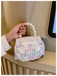 Detail van lavendel kinderhandtas met bloemenborduurwerk en parel handvat