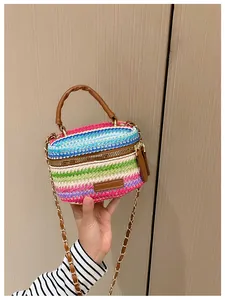 Detail of colorful woven straw mini bag with brown leather handles and gold chain strap
