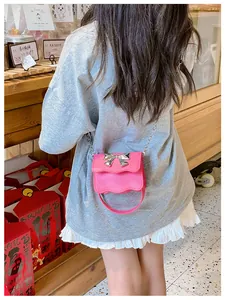Close-up of pink PU leather girls' crossbody bag with silver bow and chain strap