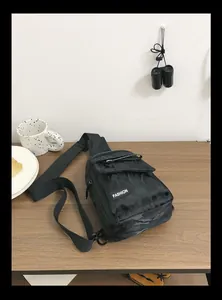Detail of black camo nylon sling bag with Fashion label on a wooden surface