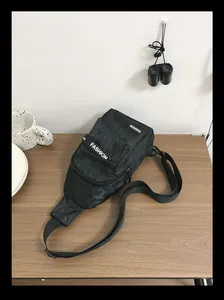 Detail of nylon sling bag with shadow camo pattern and fashion label on wooden table