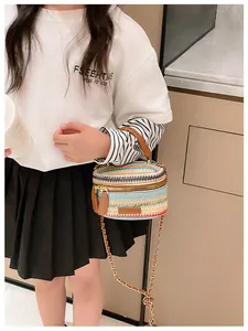 Detail of colorful woven cylinder crossbody bag with golden chain and leather handle