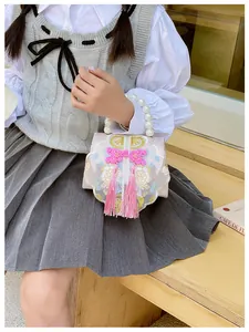 Detail of pink embroidered girls' bag with pearl handle, floral pattern and silk tassels