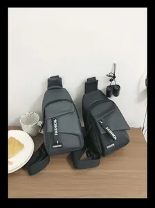 Detail view of two nylon sports chest bags in dark grey and black on a wooden table