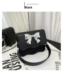 Detail of black mini PU leather bag with silver metal bow and wavy edge design