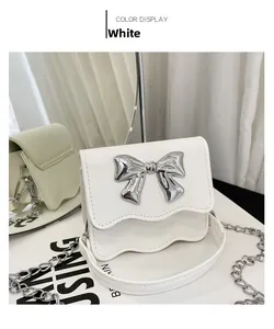 Detail of white PU leather crossbody bag with silver bow and scalloped edge flap