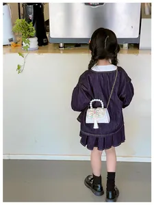 Girl wearing mini pearl handle handbag with floral embroidery and white tassel detail