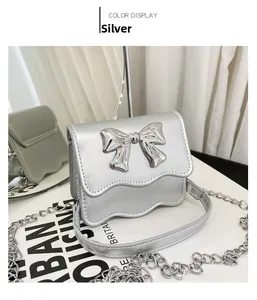 Detail of silver PU mini crossbody bag featuring a bow buckle and wavy scalloped edge flap