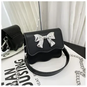 Detail of PU leather shoulder bag with a large silver bow and wavy flap design